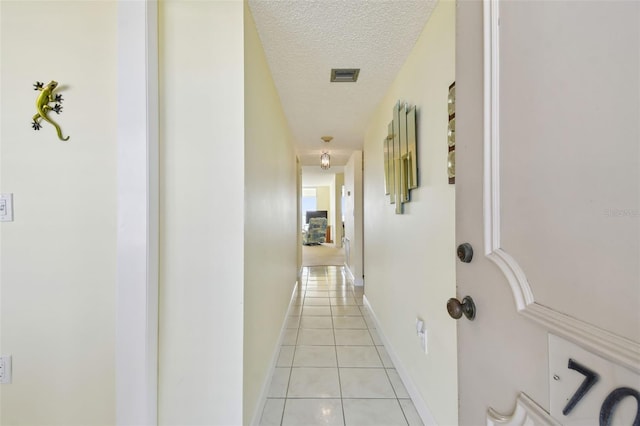 hall featuring light tile patterned floors and a textured ceiling