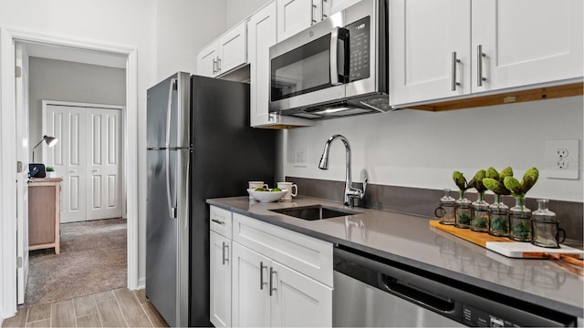 kitchen featuring white cabinets, stainless steel appliances, light colored carpet, and sink