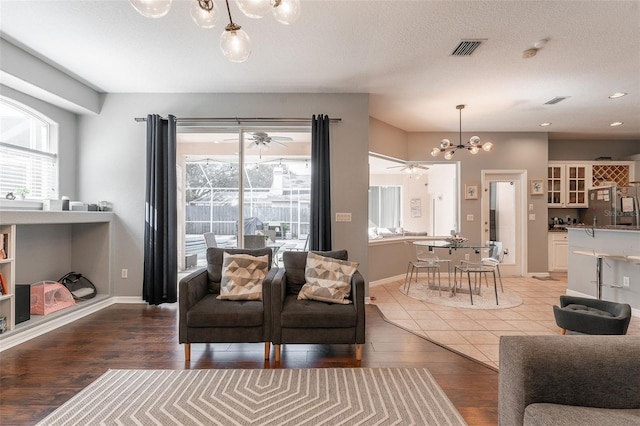 living room featuring hardwood / wood-style floors, ceiling fan with notable chandelier, a healthy amount of sunlight, and a textured ceiling