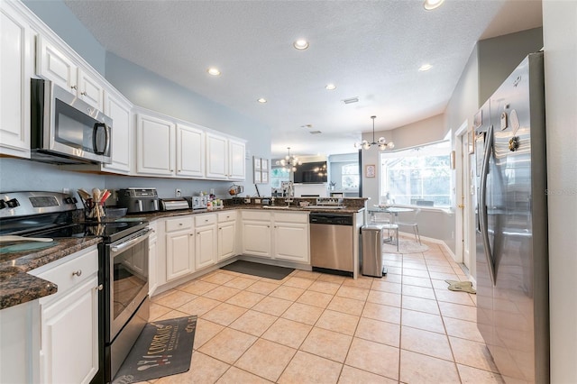 kitchen featuring hanging light fixtures, kitchen peninsula, a chandelier, white cabinets, and appliances with stainless steel finishes