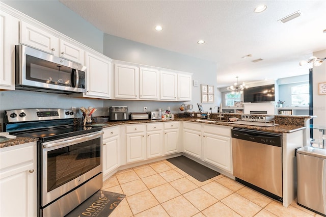 kitchen featuring white cabinets, stainless steel appliances, and dark stone counters