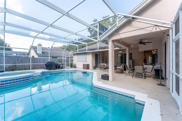 view of pool featuring glass enclosure, ceiling fan, grilling area, an in ground hot tub, and a patio