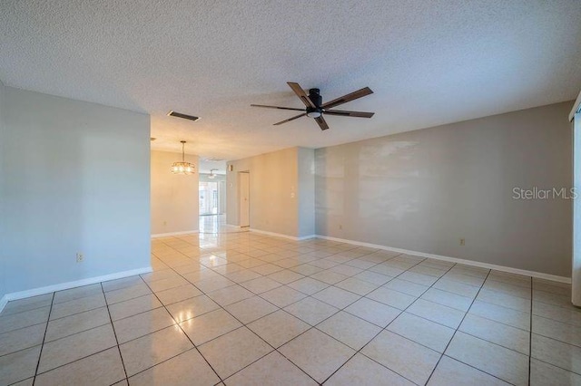 tiled empty room with a textured ceiling and ceiling fan with notable chandelier