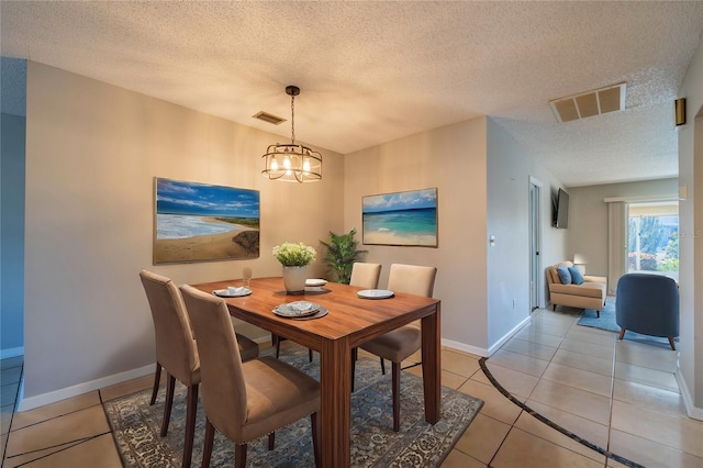 dining space with a chandelier, a textured ceiling, and light tile patterned flooring