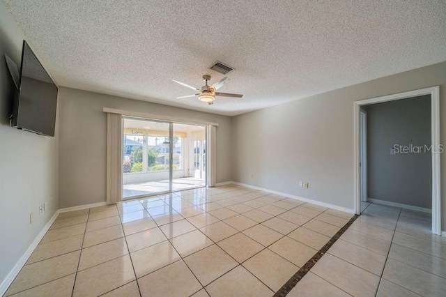 empty room with a textured ceiling, ceiling fan, and light tile patterned flooring