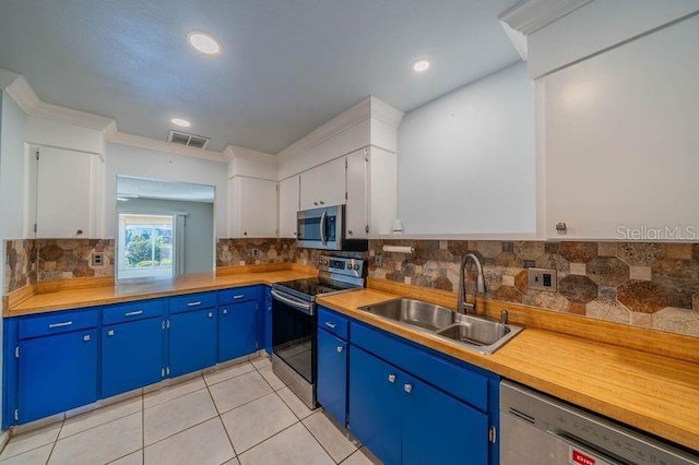 kitchen featuring stainless steel appliances, blue cabinets, sink, light tile patterned floors, and white cabinets