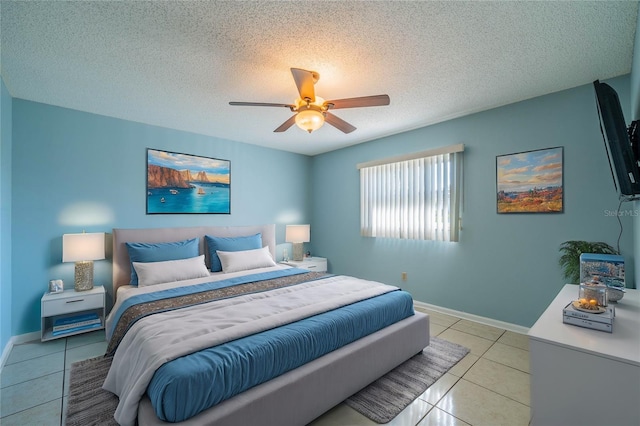 bedroom with ceiling fan, light tile patterned floors, and a textured ceiling