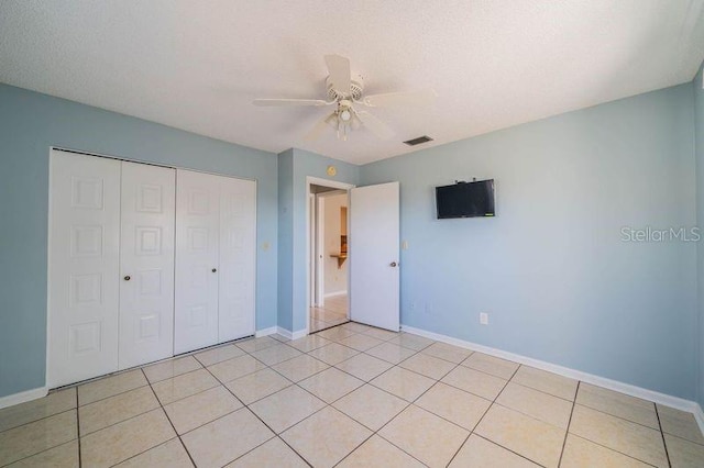 unfurnished bedroom with light tile patterned floors, a textured ceiling, a closet, and ceiling fan