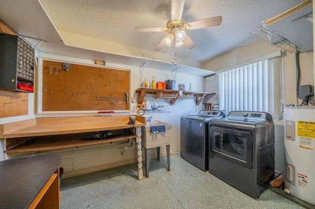 laundry room with a textured ceiling, a workshop area, ceiling fan, water heater, and washing machine and clothes dryer