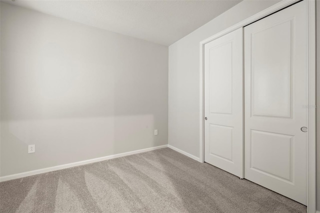 unfurnished bedroom featuring light colored carpet and a closet