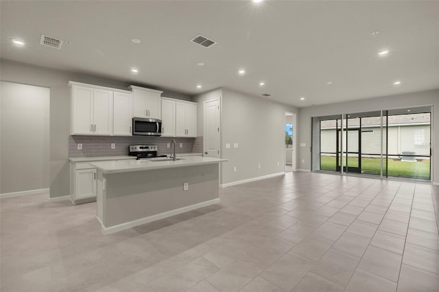 kitchen with appliances with stainless steel finishes, sink, a center island with sink, and white cabinets