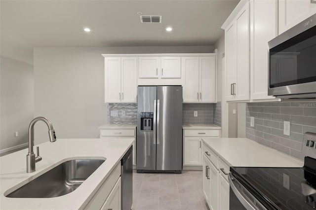 kitchen with sink, light tile patterned floors, backsplash, stainless steel appliances, and white cabinets