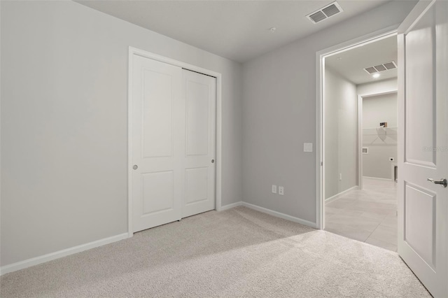 unfurnished bedroom featuring light carpet and a closet