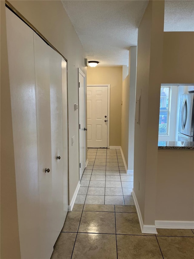 corridor featuring light tile patterned flooring and a textured ceiling