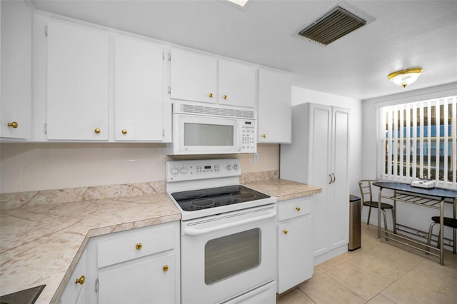 kitchen with white cabinets, light tile patterned floors, and white appliances