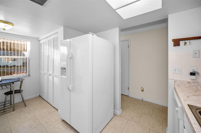 kitchen with sink, light tile patterned flooring, and white refrigerator with ice dispenser