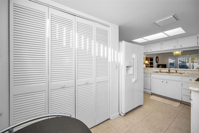 kitchen with white cabinets, light tile patterned floors, white appliances, and sink