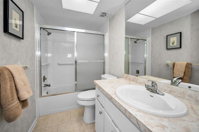 full bathroom with a skylight, vanity, shower / bath combination with glass door, tile patterned flooring, and toilet