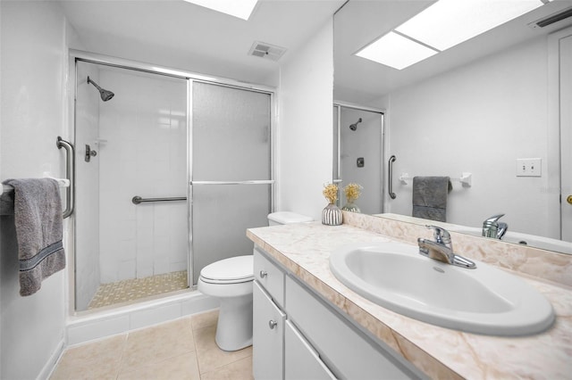 bathroom featuring a skylight, vanity, tile patterned flooring, toilet, and a shower with shower door