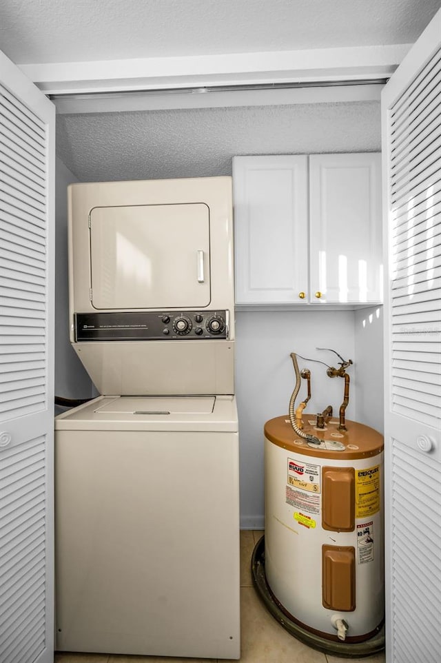 clothes washing area with cabinets, light tile patterned floors, stacked washer / dryer, and water heater