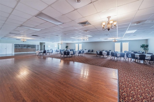 workout area with a drop ceiling, wood-type flooring, and a notable chandelier