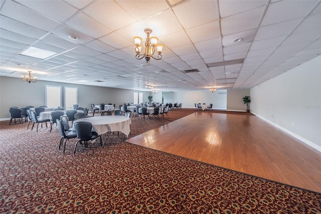 unfurnished dining area with a paneled ceiling, a notable chandelier, and carpet floors