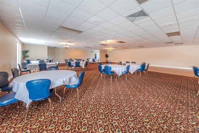 carpeted dining room with a paneled ceiling