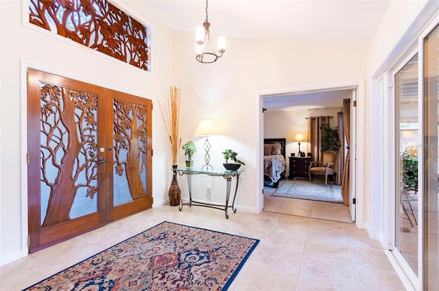 foyer entrance featuring french doors, a towering ceiling, an inviting chandelier, and light tile patterned flooring