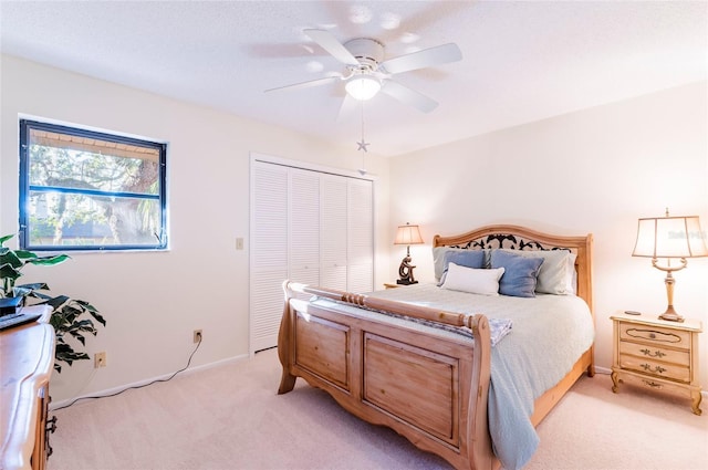 bedroom with ceiling fan, light carpet, and a closet