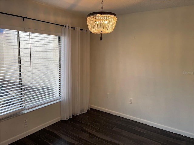 spare room featuring dark hardwood / wood-style floors and a chandelier