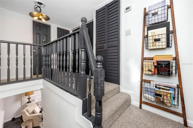 stairway with a textured ceiling and carpet flooring