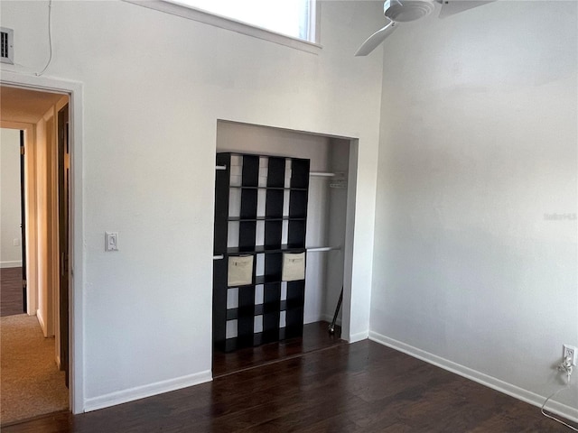 unfurnished bedroom with ceiling fan, dark wood-type flooring, and a closet