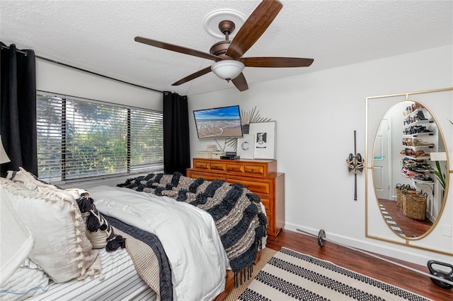 bedroom with ceiling fan, a textured ceiling, and hardwood / wood-style flooring