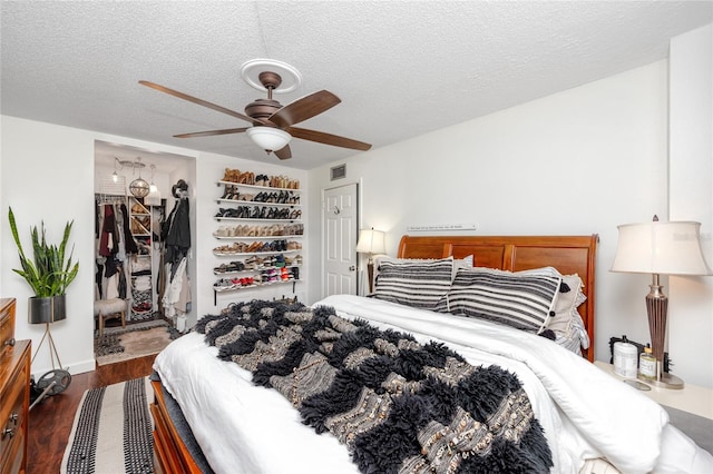 bedroom featuring ceiling fan, a closet, dark wood-type flooring, and a textured ceiling