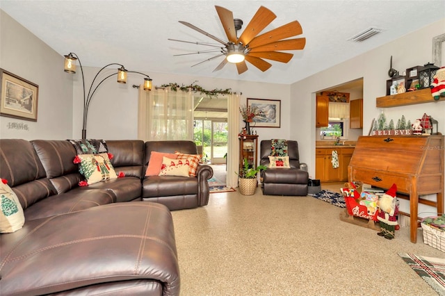 living room featuring ceiling fan and a textured ceiling