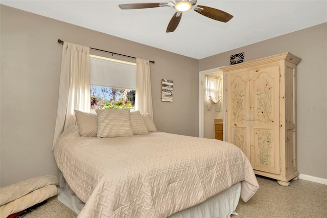 carpeted bedroom with ensuite bathroom and ceiling fan