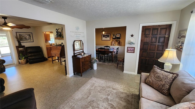 living room with ceiling fan and a textured ceiling