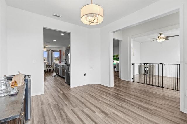 dining room featuring ceiling fan with notable chandelier and light hardwood / wood-style flooring