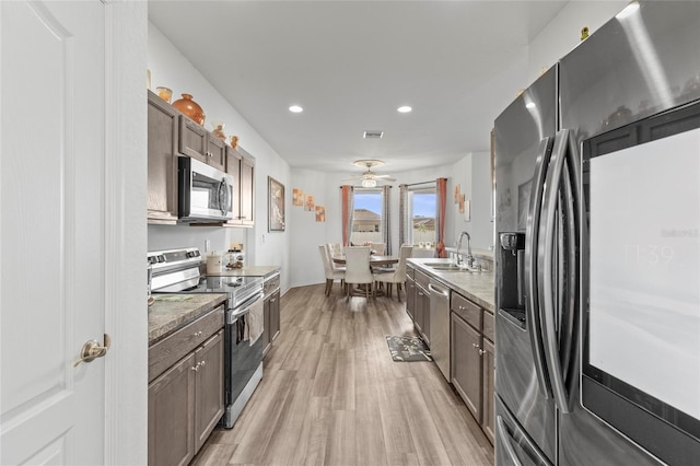 kitchen with appliances with stainless steel finishes, light wood-type flooring, dark brown cabinets, ceiling fan, and sink