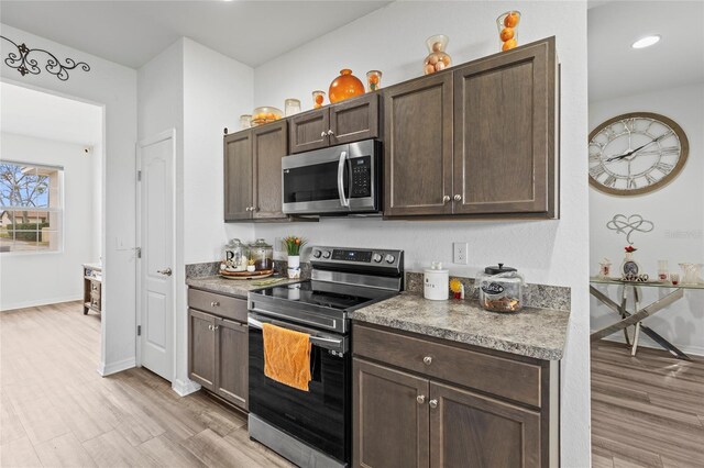 kitchen featuring dark brown cabinets, stainless steel appliances, and light hardwood / wood-style flooring