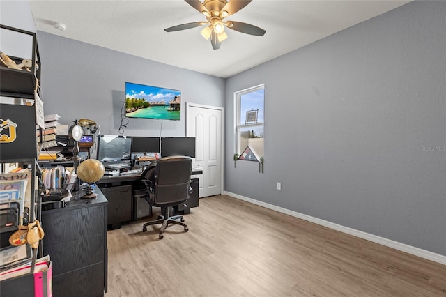 home office with light wood-type flooring and ceiling fan