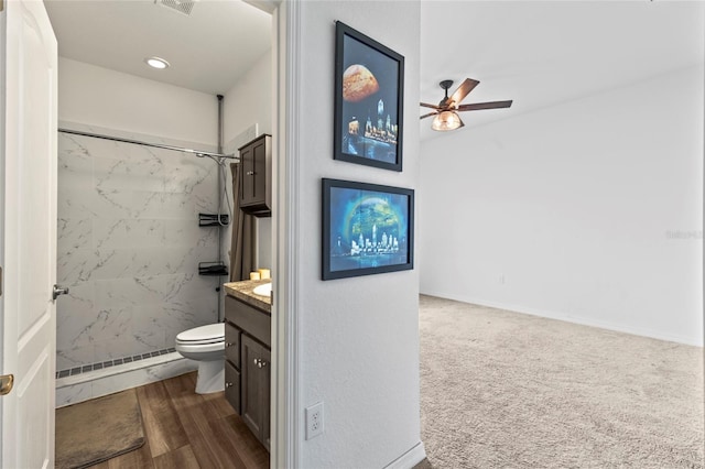 bathroom featuring vanity, ceiling fan, toilet, tiled shower, and a baseboard radiator