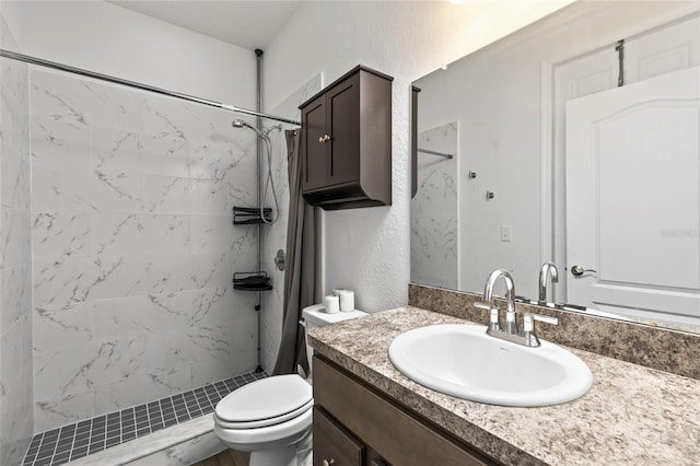 bathroom with tiled shower, vanity, and toilet