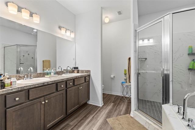 full bathroom featuring vanity, toilet, wood-type flooring, and shower with separate bathtub