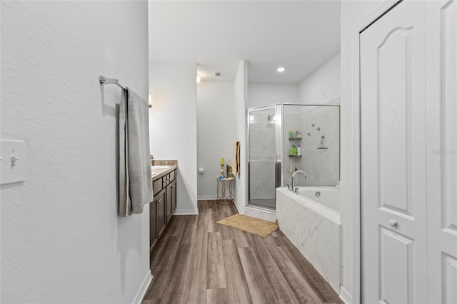 bathroom featuring hardwood / wood-style floors, vanity, and shower with separate bathtub