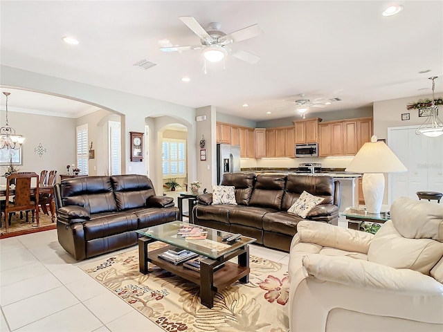 living room featuring ceiling fan with notable chandelier, light tile patterned flooring, and ornamental molding