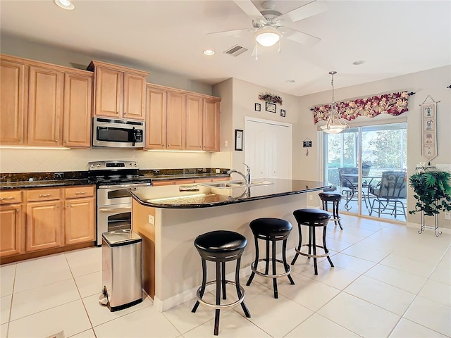 kitchen featuring appliances with stainless steel finishes, sink, pendant lighting, a center island with sink, and light tile patterned flooring