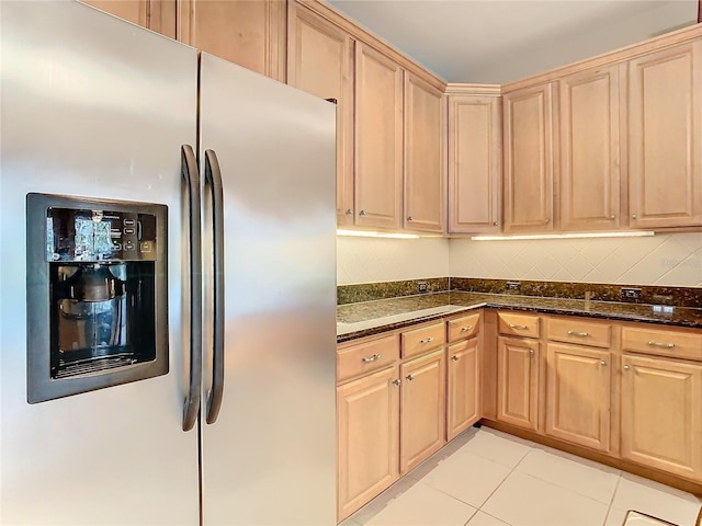 kitchen featuring light brown cabinets, dark stone countertops, stainless steel fridge with ice dispenser, and light tile patterned floors