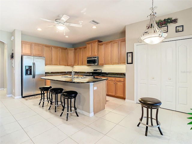 kitchen with appliances with stainless steel finishes, ceiling fan, a kitchen island with sink, sink, and light tile patterned floors