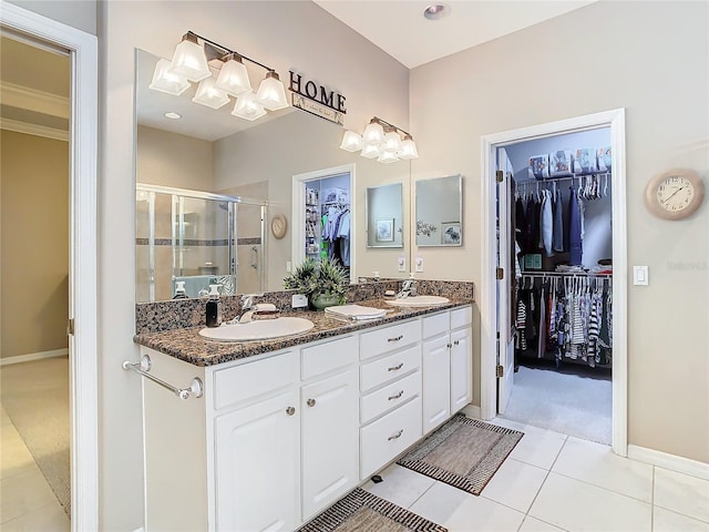 bathroom featuring tile patterned floors, vanity, a shower with shower door, and ornamental molding